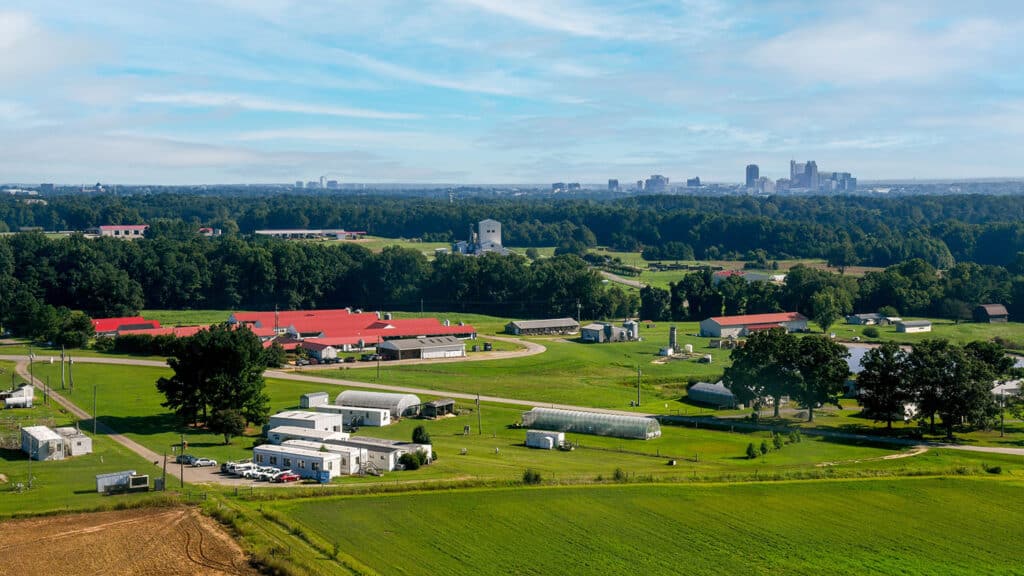 Aerial view of Lake Wheeler Field Labs with the downtown Raleigh skyline showing in the upper background.-