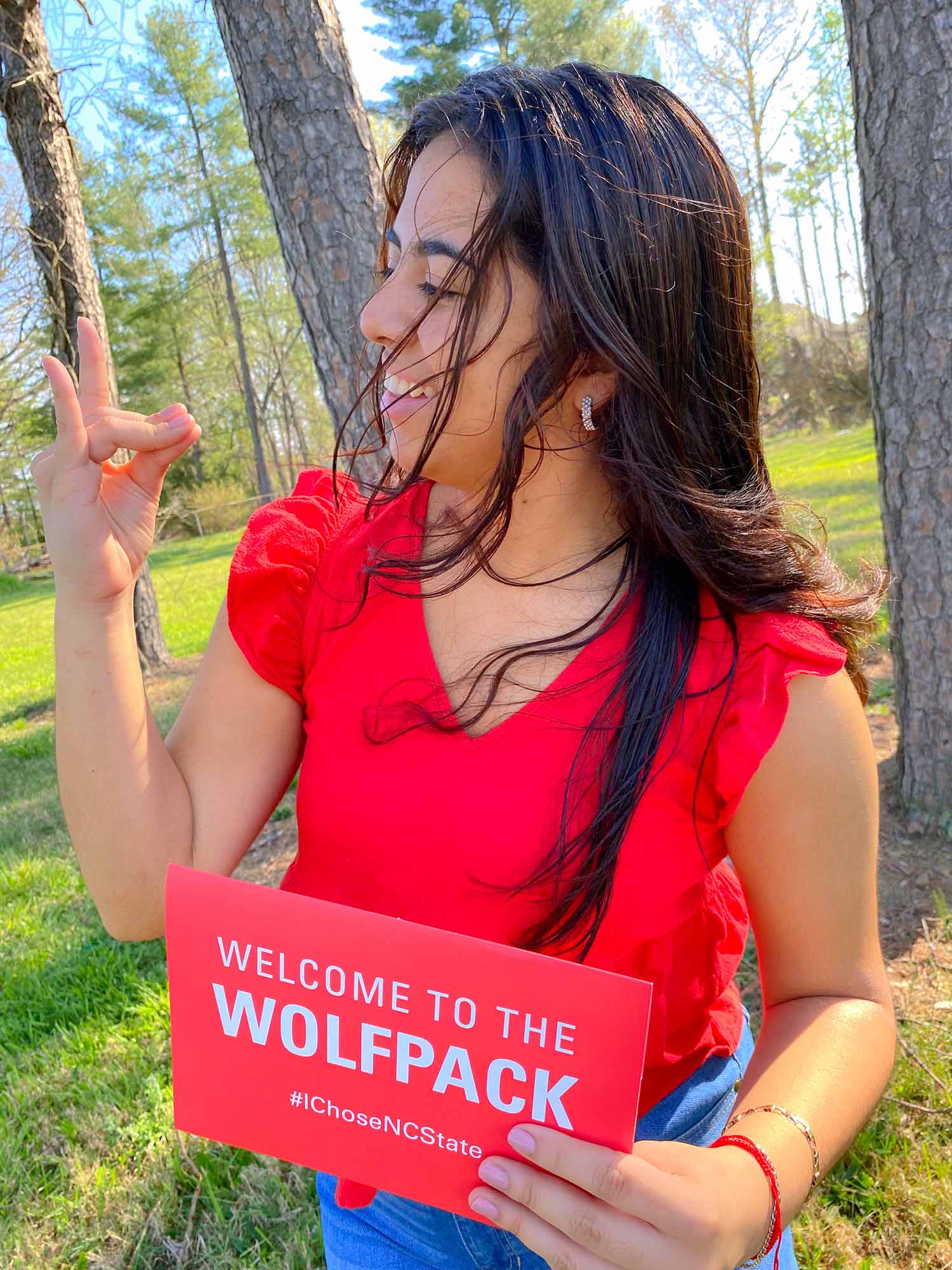 Incoming student Katie Alcaraz holds up wolf ears and her red envelope, which contains her acceptance letter to NC State.