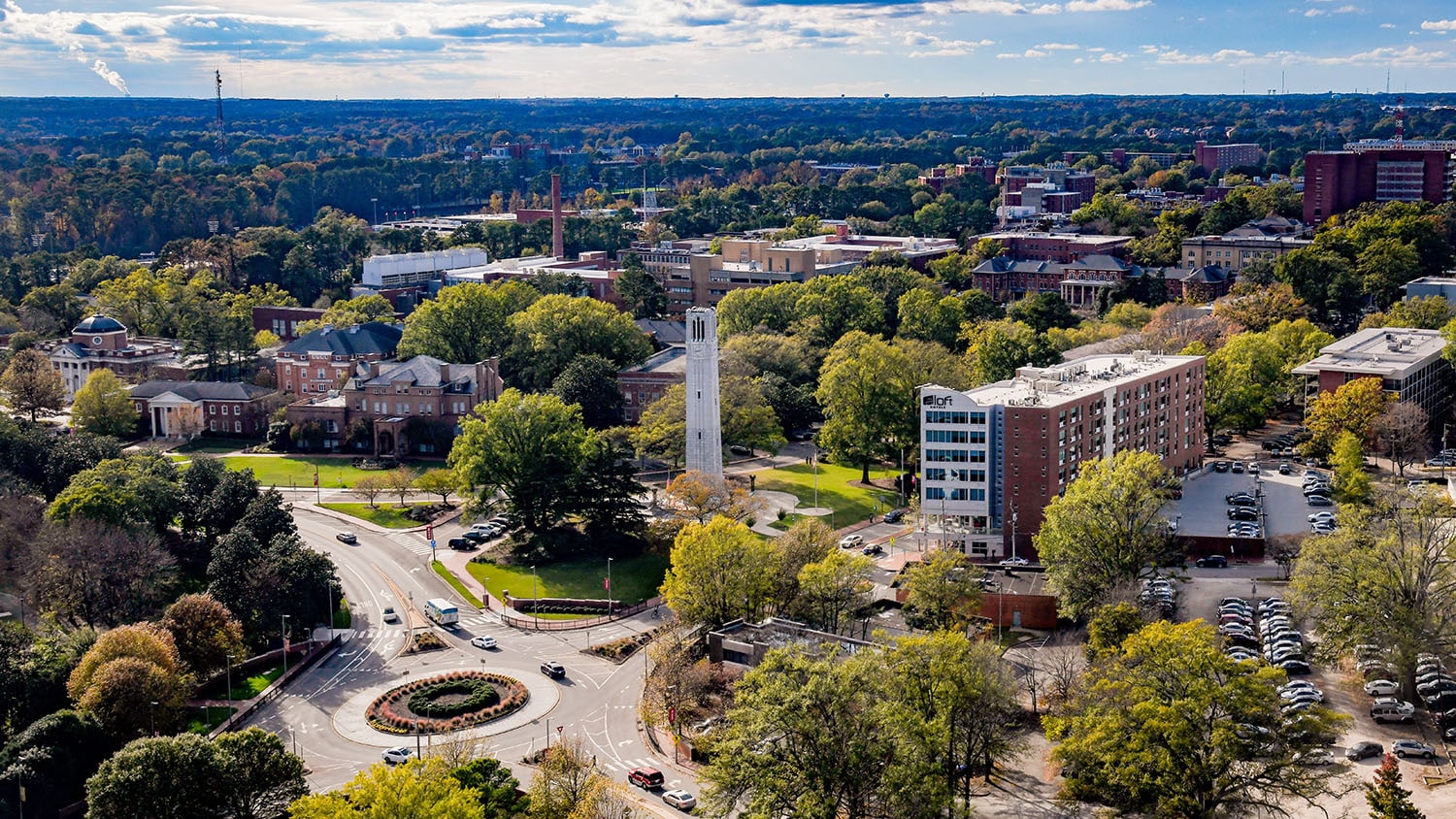 An aerial view of NC State's main campus, with the Memorial Belltower featured in the center foreground.