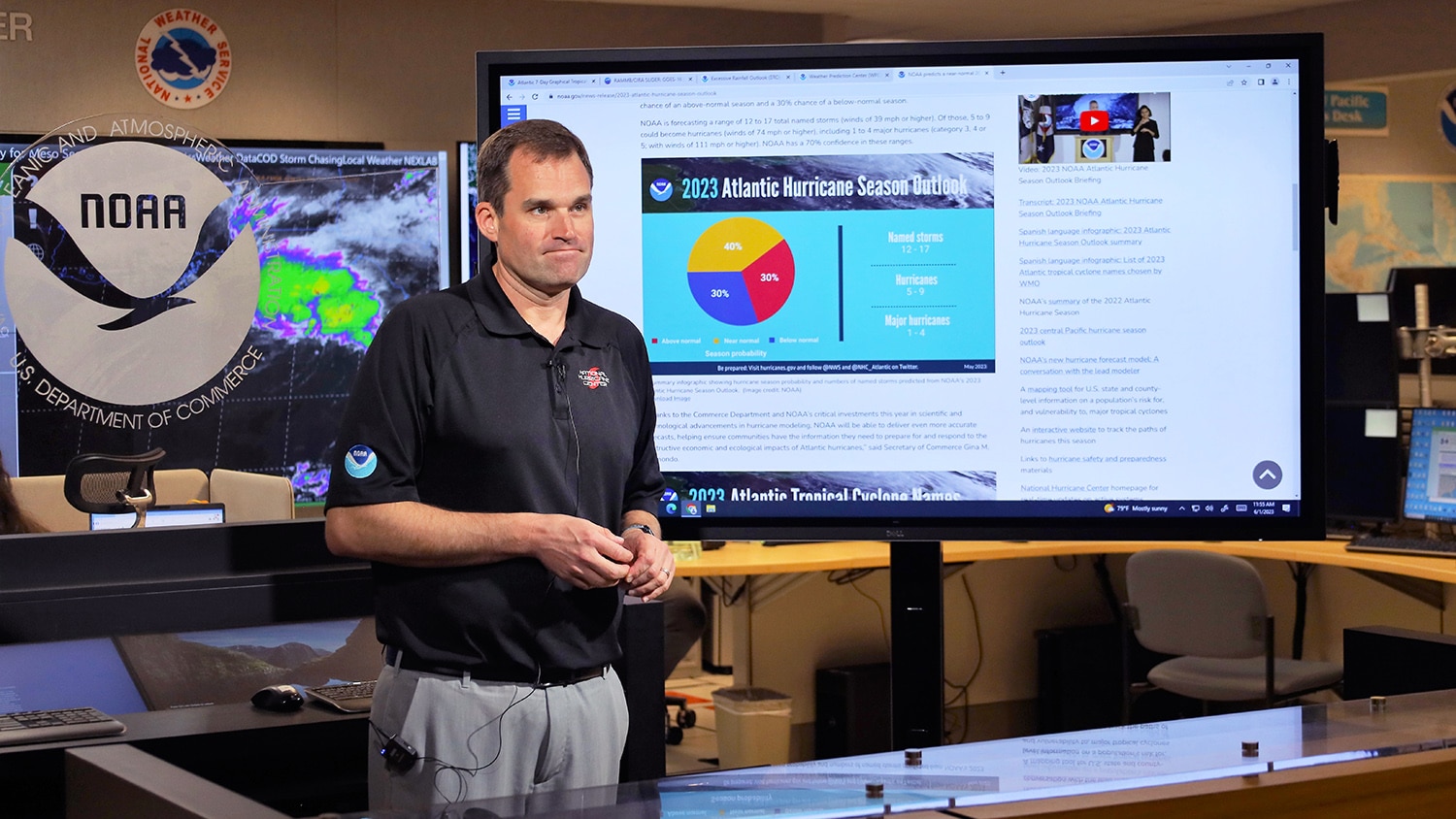 Michael Brennan stands in front of a large screen that displays a graphic about the 2023 hurricane season.