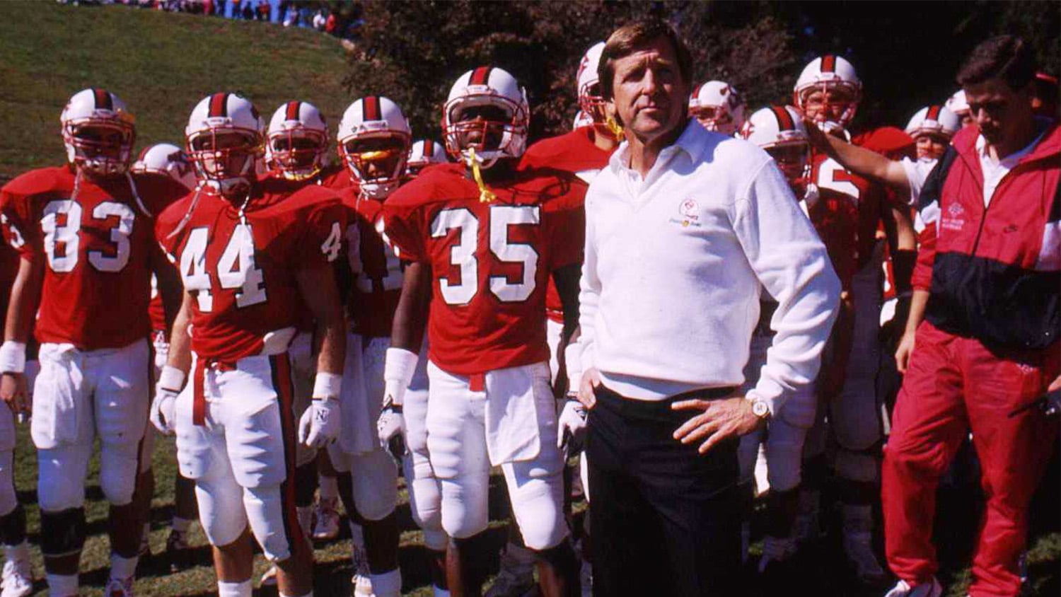 Dick Sheridan stands at the front of a group of uniformed NC State football players