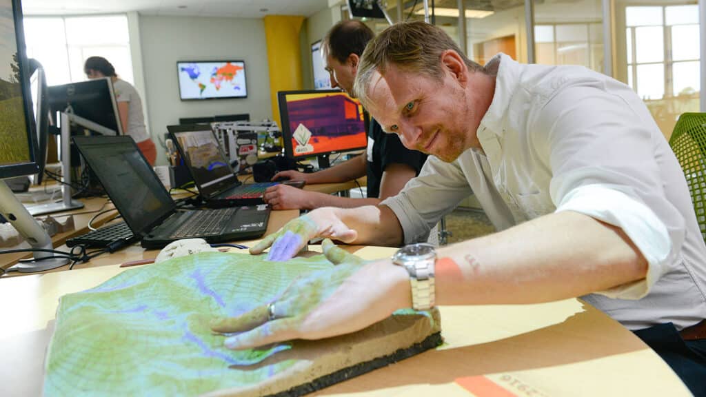 Ross Meentemeyer, director of the Center for Geospatial Analytics, examines a three-dimensional model of terrain in the center's Geospatial Visualization Lab.
