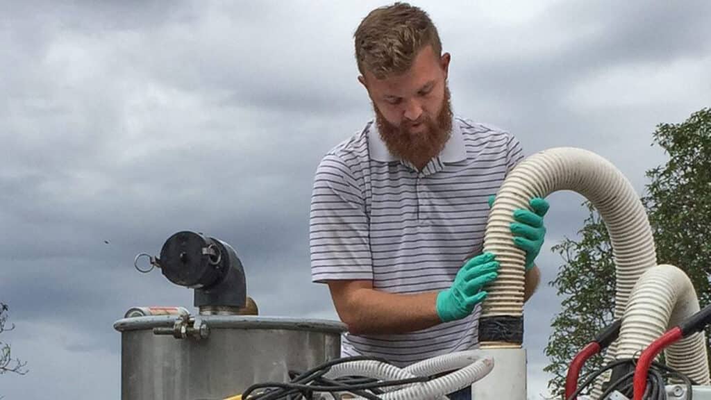 A researcher with the Global WaSH cluster works with the Flexcrevator, a novel device equipped with a vacuum designed as an economical solution for communities to empty pit latrines.