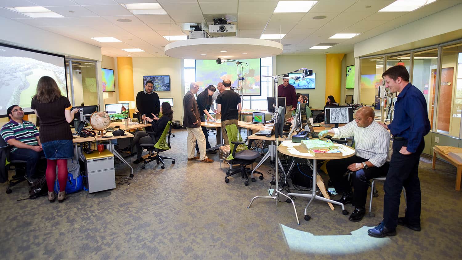 A wide shot shows researchers working on various projects in the Geospatial Visualization Lab.