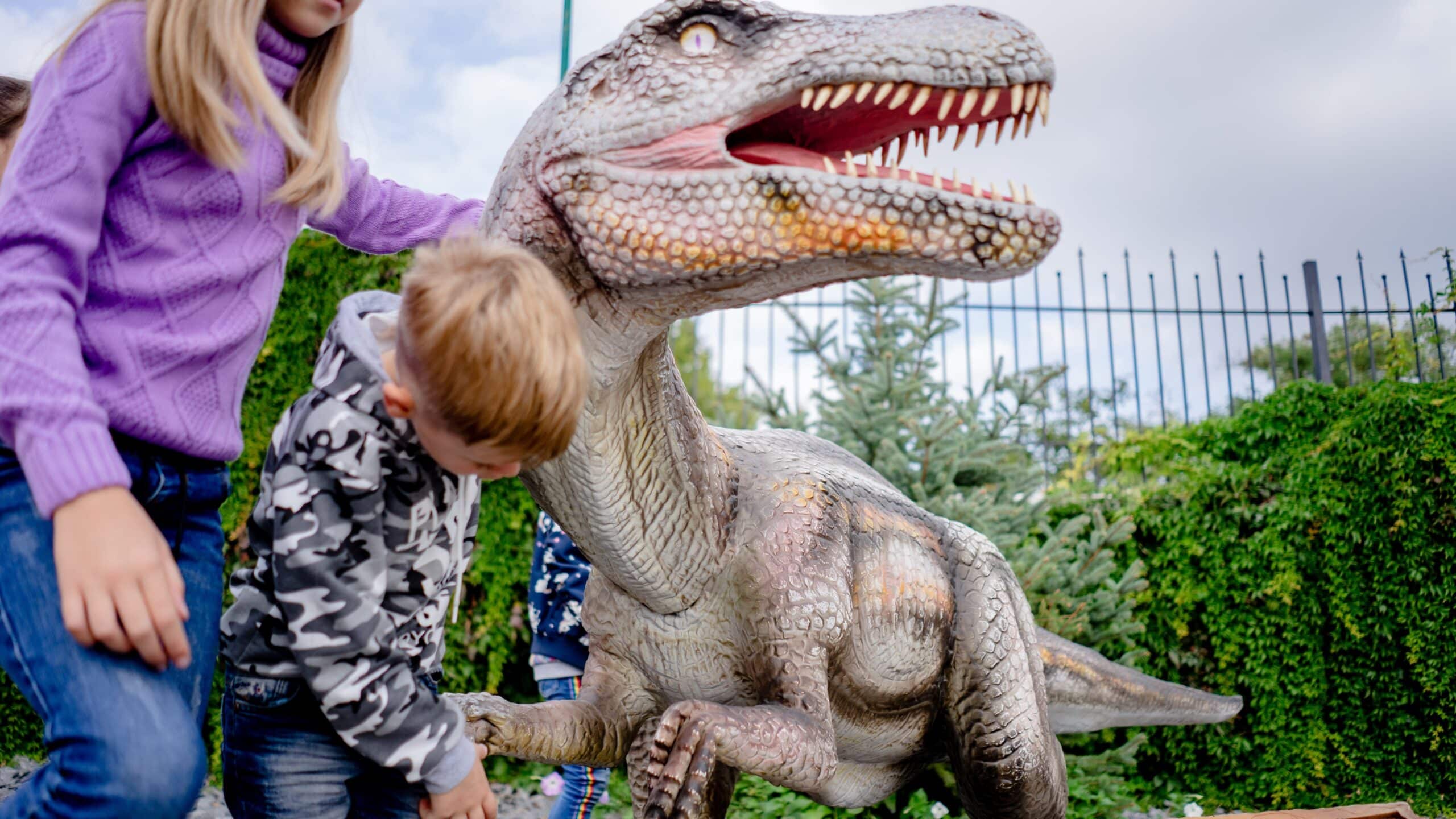 Children playing with dinosaur statue.