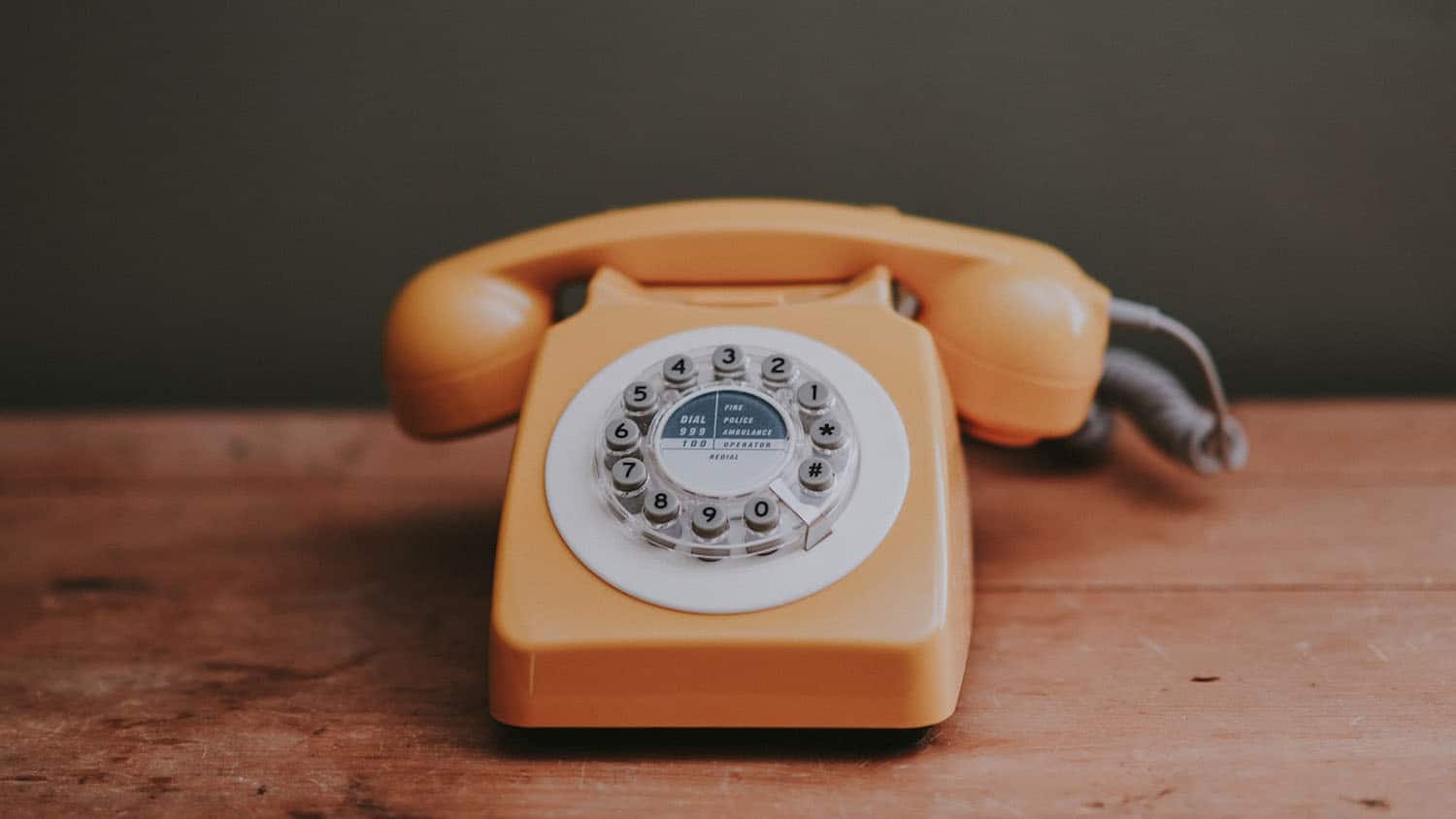 an old-fashioned rotary phone sits on a table