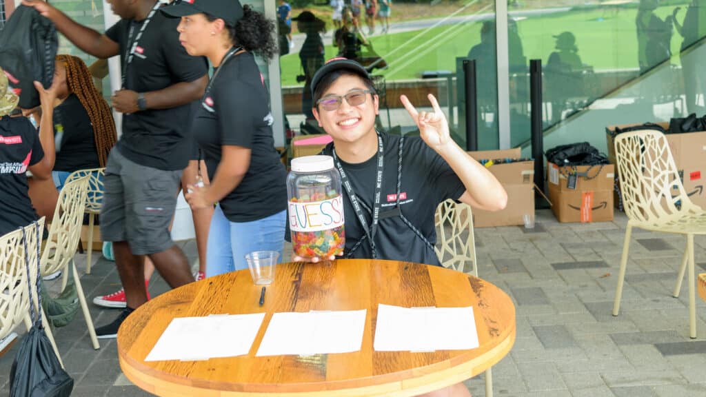 A student mentor smiles and throw up wolfies while working a game station at the Symposium's welcome event.