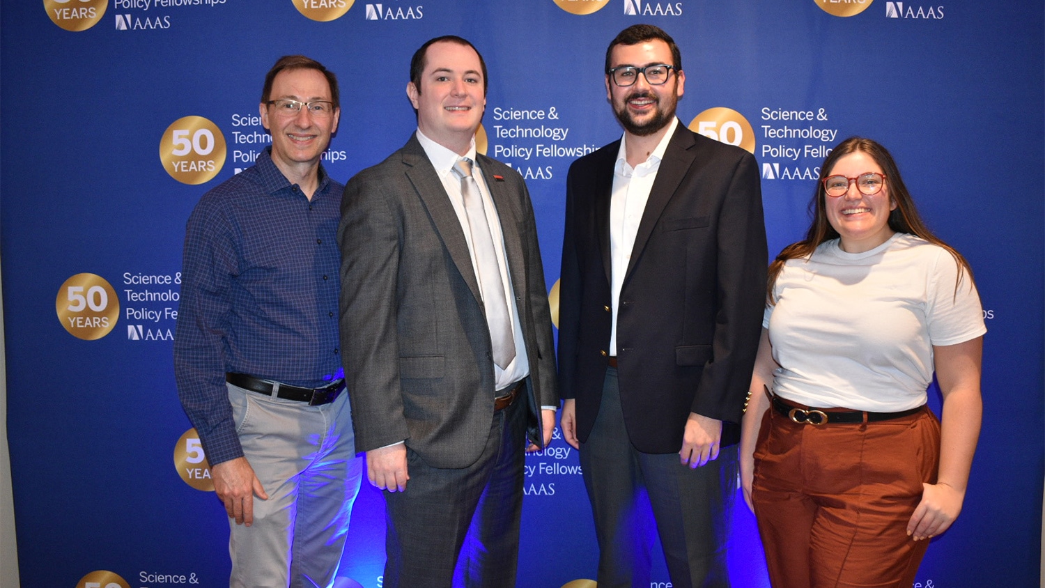 Four people in front of a backdrop that has the AAAS logo on it