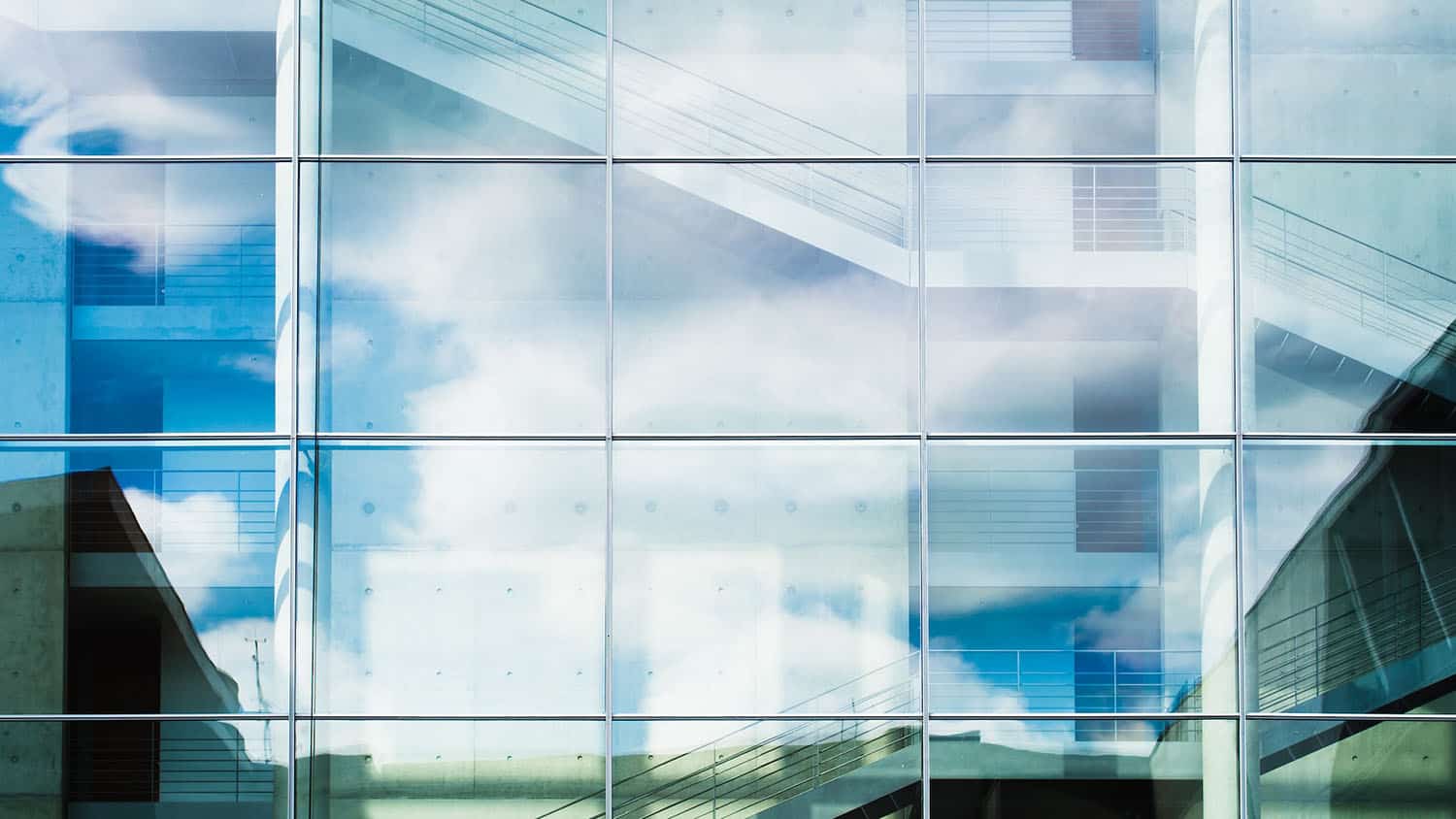 photo shows a large window into the stairwell of a building. the glass of the window reflects some light, but allows you to see some of the stairwell.