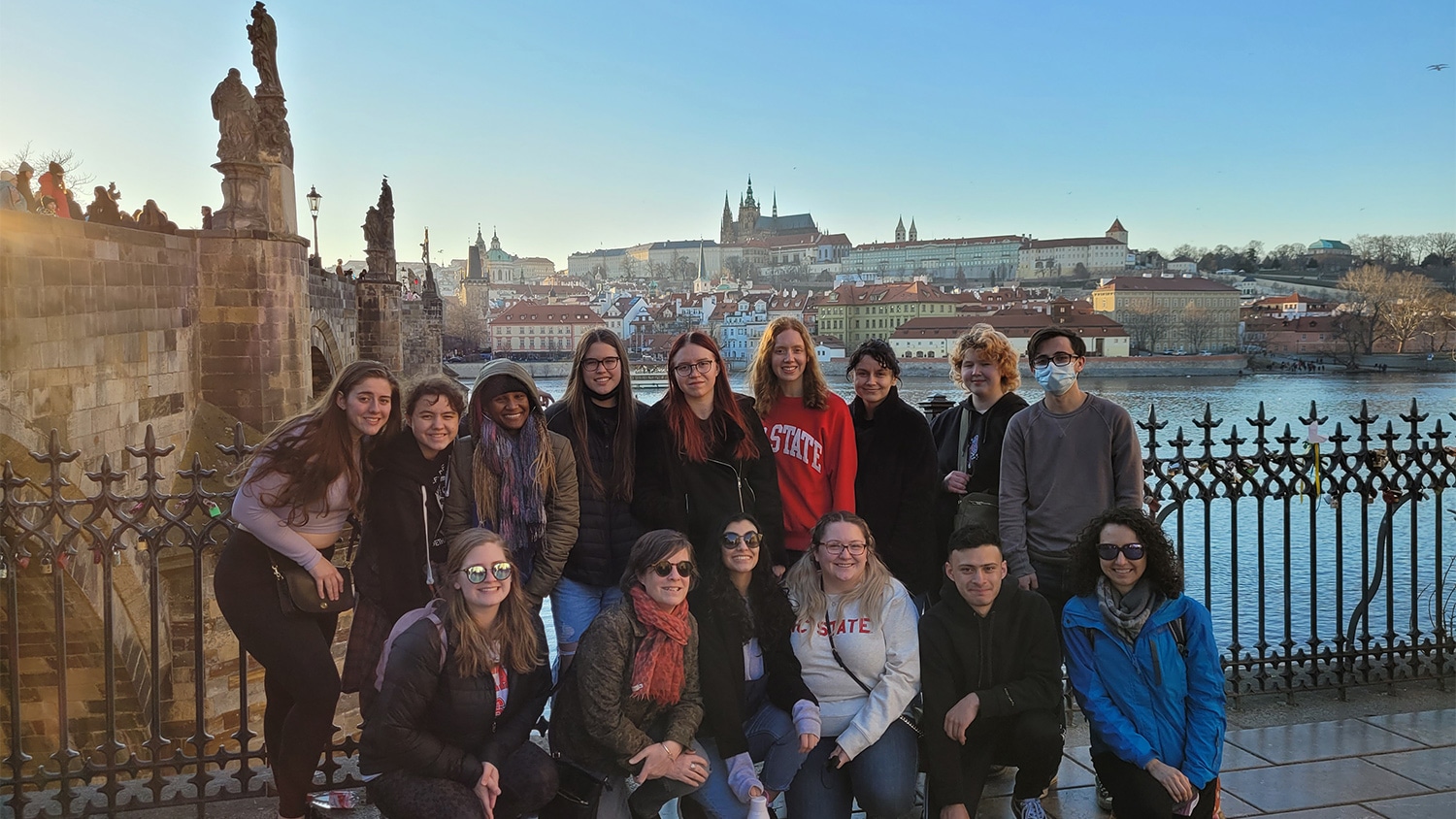 A group of students and faculty pose in front of a cityscape in Prague