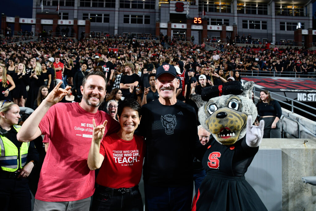 Bill Cowher poses with Mrs. Wuf and College of Education Dean Paola Sztajn in front of the stands of Carter-Finley Stadium