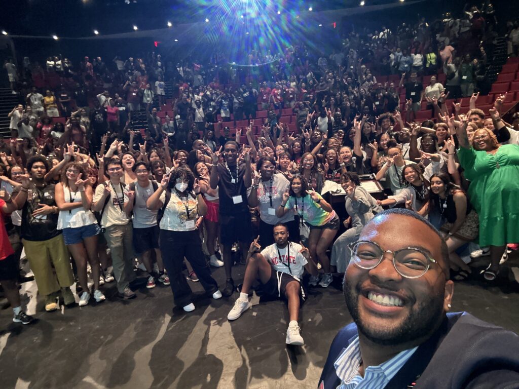 McKenzie takes a selfie in front of a large group of students in Stewart Theatre.