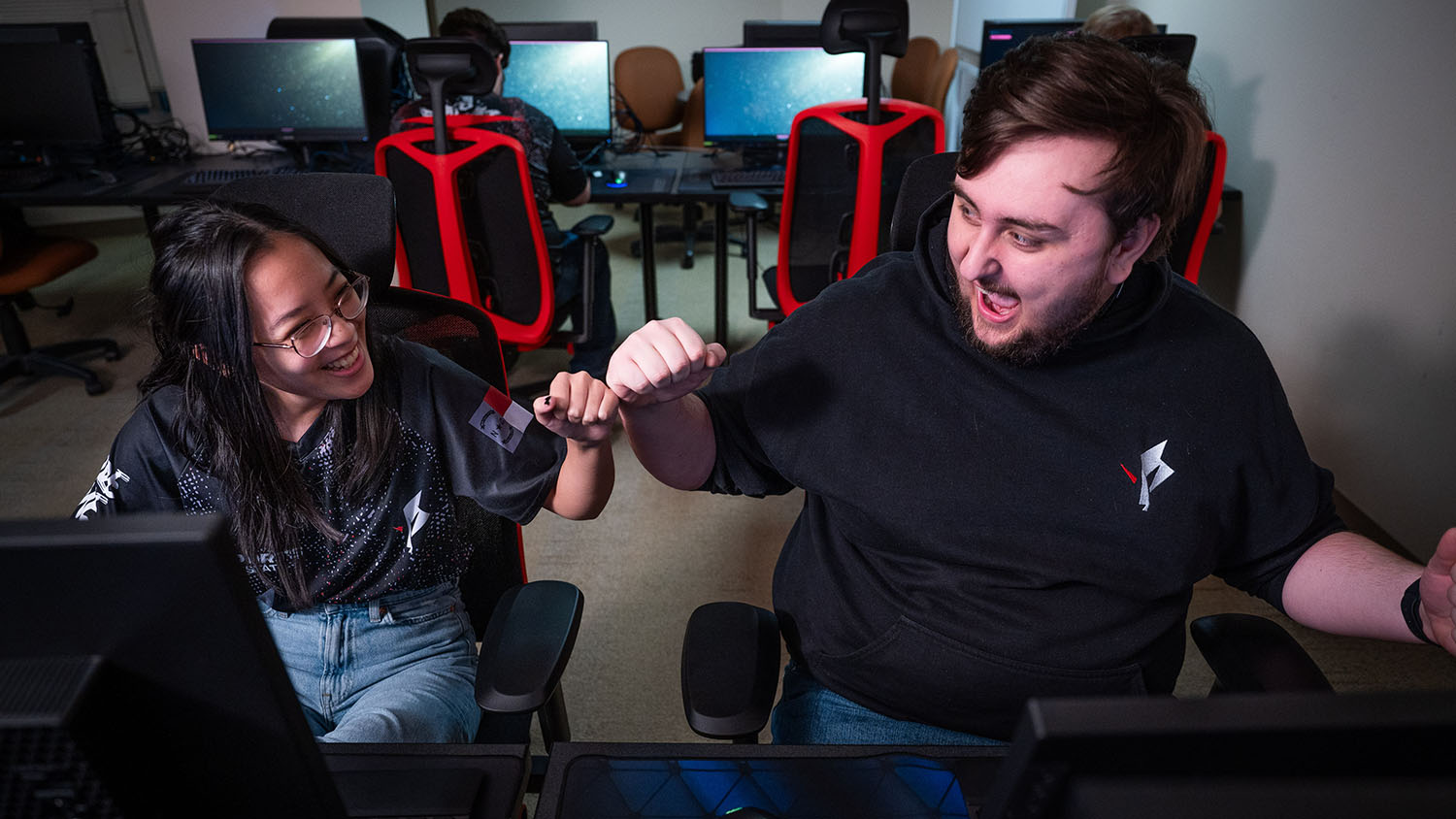 Two members of the Esports Club celebrate victory with a fist bump in an on-campus gaming space.