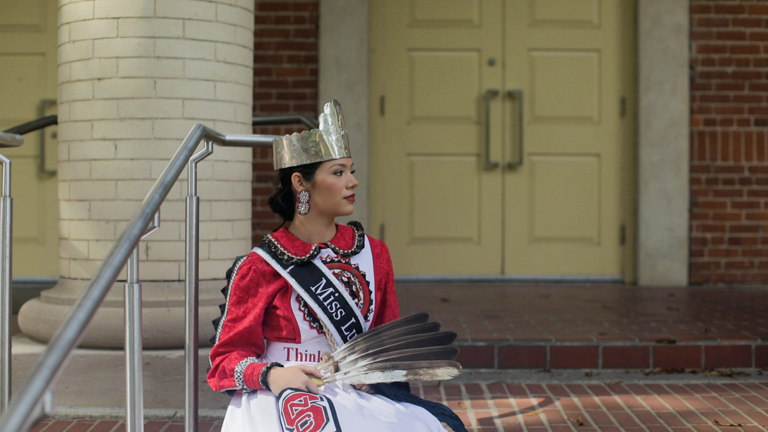 Ashtyn Thomas sits on the steps of Leazar Hall in her traditional Lumbee regalia.
