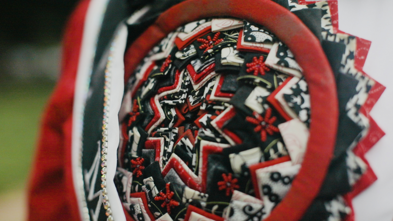 Close up image of the traditional Lumbee pinecone patchwork in the NC State colors of red, white and black.
