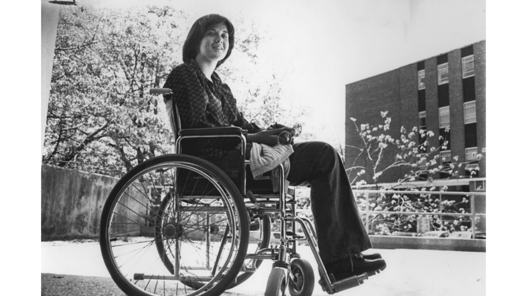 A black and white image from 1997-1981 of a student in wheelchair on campus.