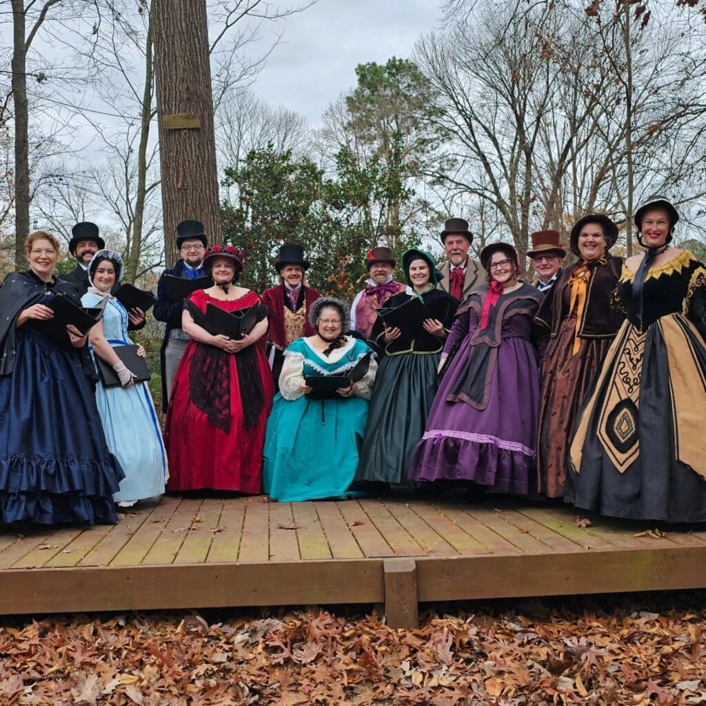 The Oakwood Waits posing as a group on a wooden stage at Fairfax Hills Park