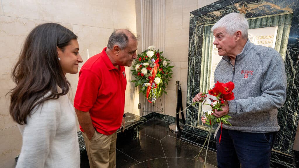 Inside the Memorial Belltower's shrine room, Kemmia and Hushang Ghodrat listen to Tom Stafford, who is holding poppies that symbolize remembrance of World War I. 