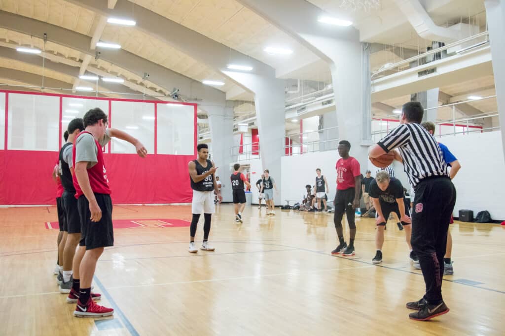 A referee prepares to toss the ball to a player at the free throw line during an intramural basketball game