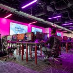 A wide view of the new NC State Gaming and Esports Lab, showing students gaming on computers in a room with purple lighting