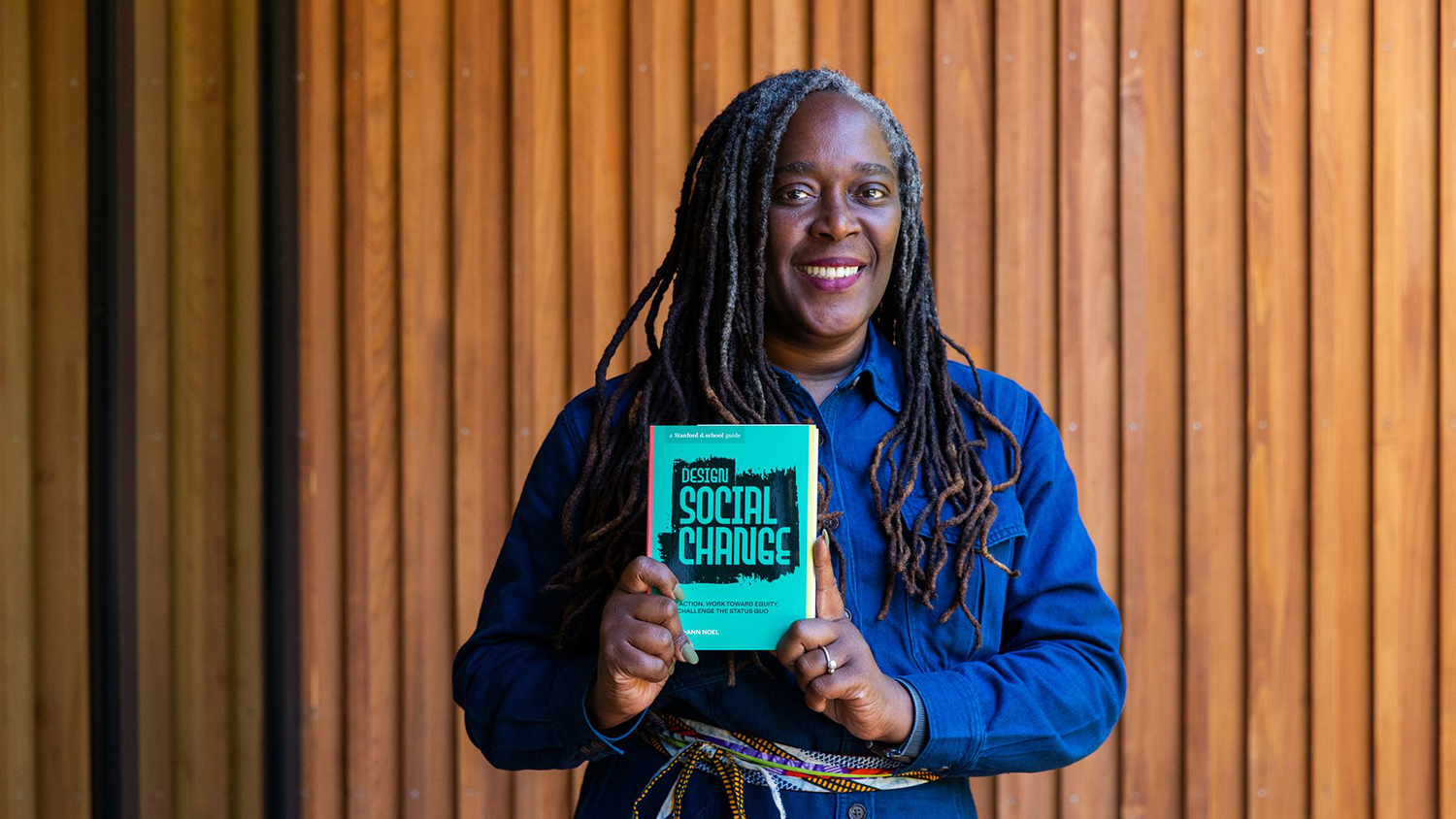 Portrait of Lesley-Ann Noel holding her recently published book, "Design Social Change."