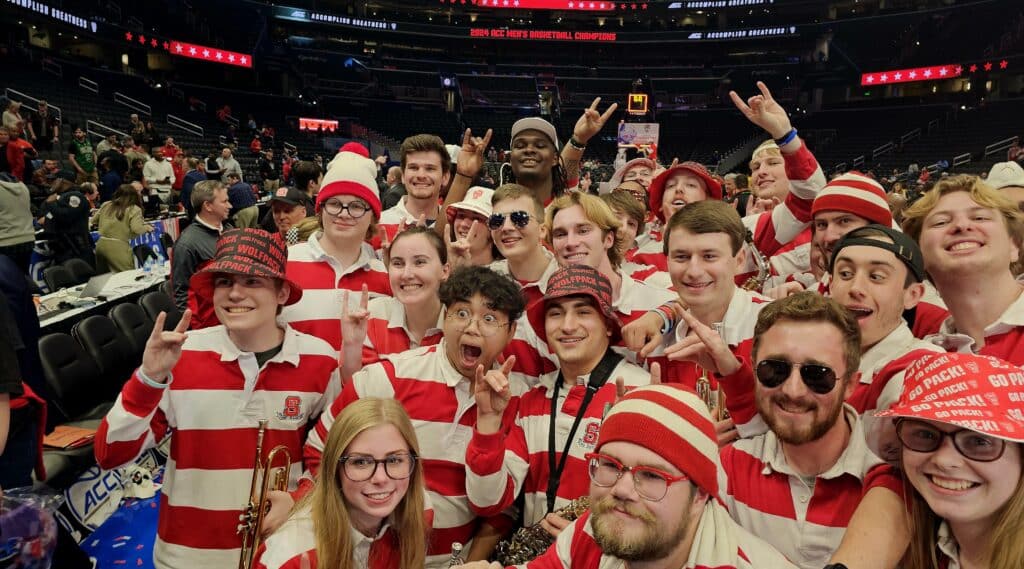 DJ Burns Jr. and members of the NC State pep band pose for a group photo on the court after the championship win
