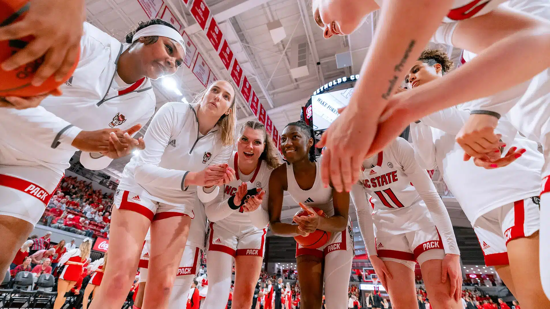 NC State women's basketball team players huddle at midcourt before a game