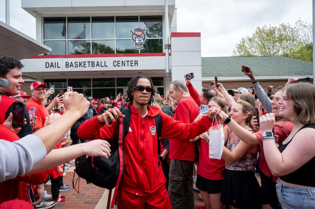 An NC State basketball player in street clothes walks through a long line of NC State fans gathered outside of the Dail Basketball Center before departing to play in the NCAA Men's Basketball Semifinal this weekend.