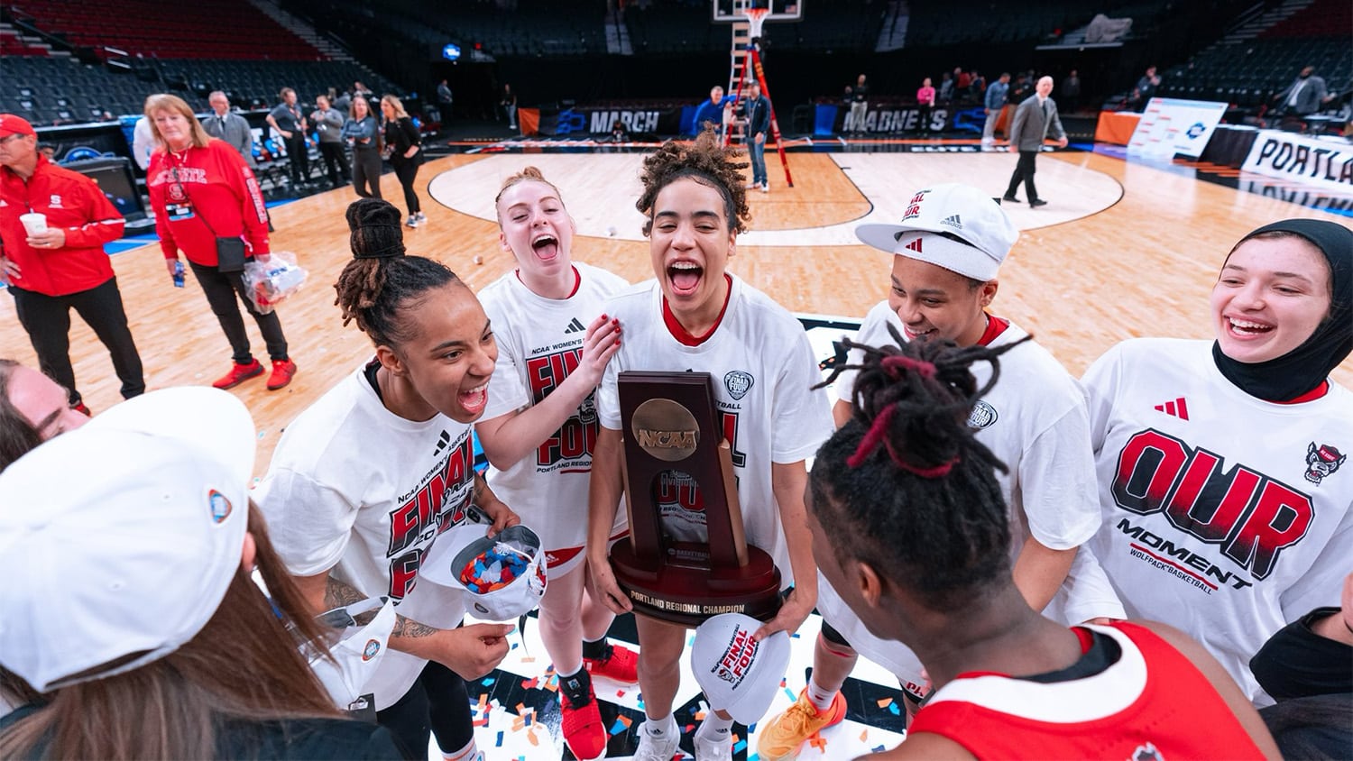 NC State Women's Basketball players celebrate on the court with their trophy after winning their game to advance to the Final Four