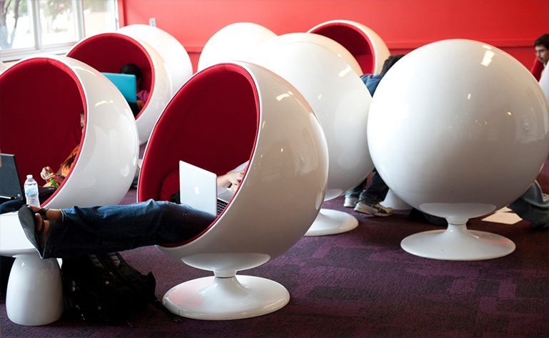 A white chair with red lining, shaped like an egg.