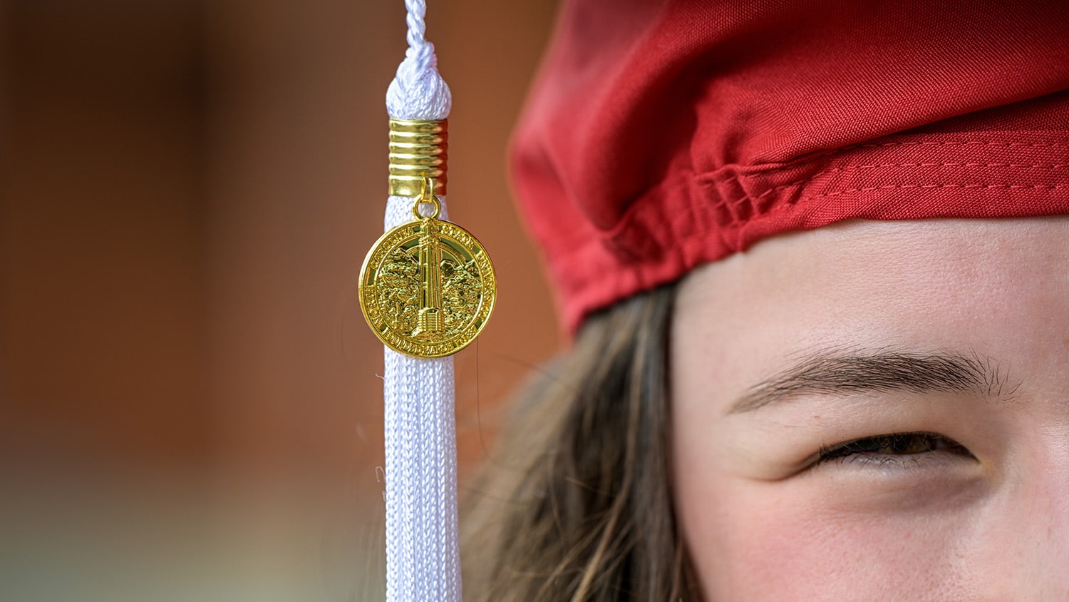 A close-up of the while and gold tassel on a graduating woman's commencement mortarboard.
