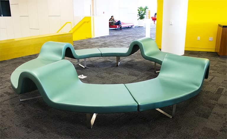 A green couch that makes a complete circle.