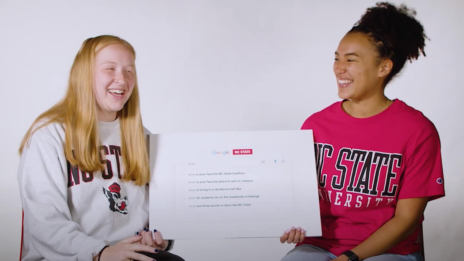 NC State students hold up a poster board containing popular questions about life at NC State.