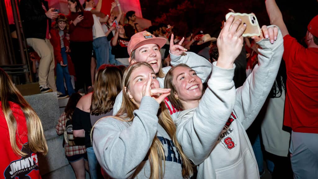 With the Wolfpack men's and women's basketball teams scoring major 2024 NCAA Championships wins, crowds of fans gather to celebrate at the Memorial Belltower.