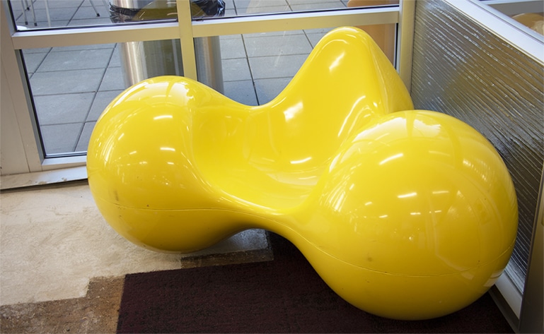 A bulbous yellow chair with space for a seat in the center.