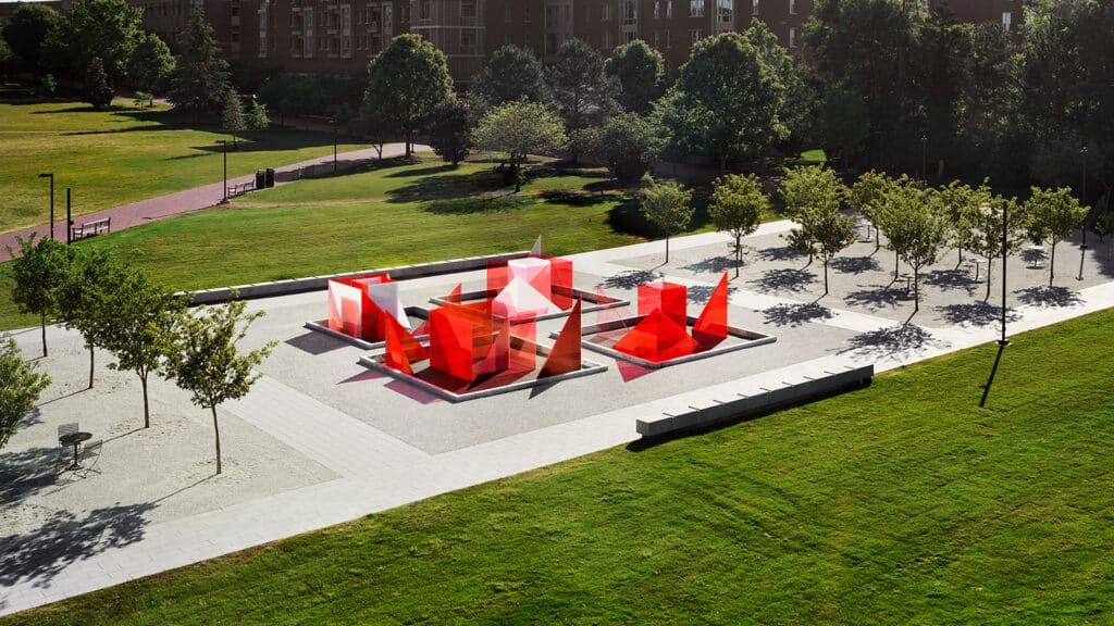 An elevated view of the Reds and Whites art installation by artist Larry Bell, showing glass red and white glass pieces clustered in a central plaza between stands of trees outside the James B. Hunt Jr. Library on Centennial Campus.