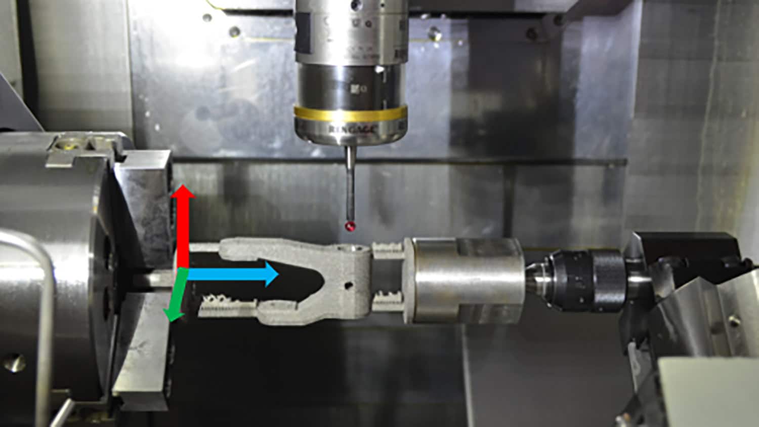 photo shows a hitch-shaped machine part clamped in a large device. a probe that is tipped with a small red sphere sits just above the machine part.
