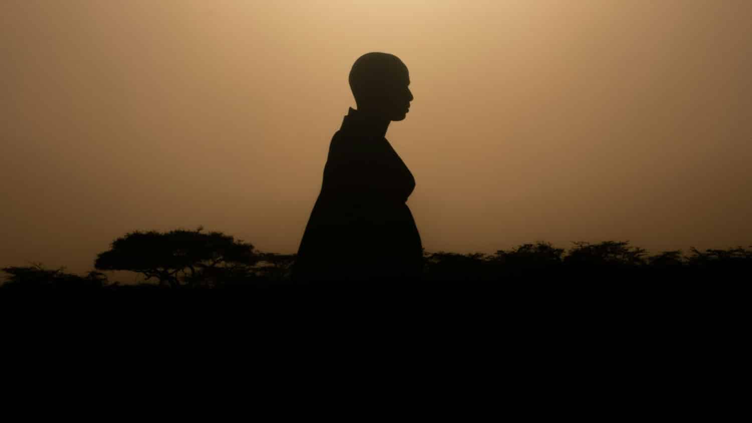 a Kenyan woman is seen in silhouette in the gloaming