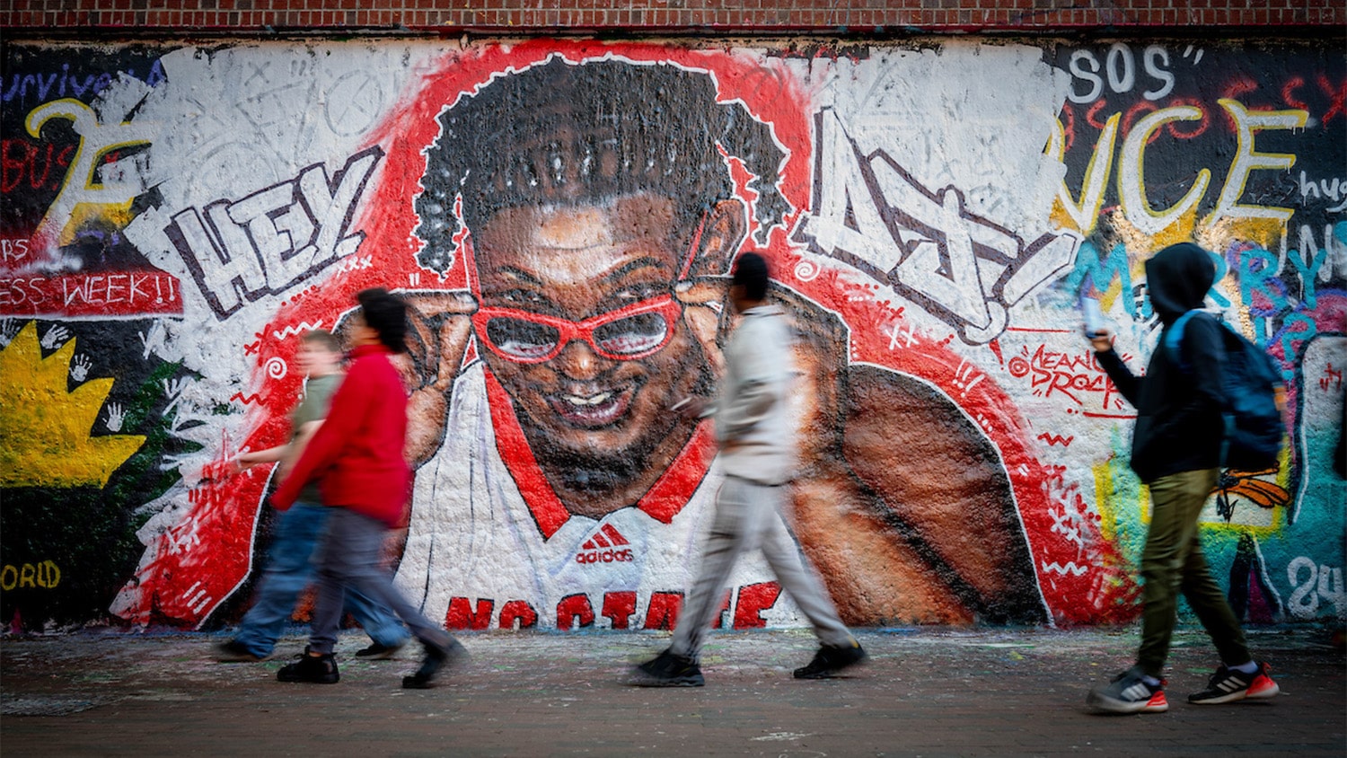 Students walk by a mural depicting men's basketball player DJ Burns at the Free Expression Tunnel