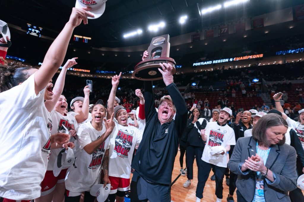 Women's basketball head coach Wes Moore and the team celebrate following their win to advance to the NCAA Women's Final Four