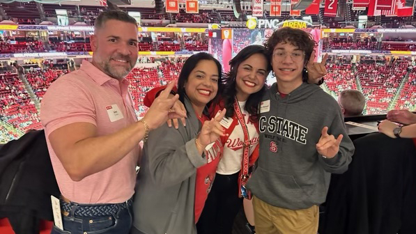 Alex Gonzalez, right, with family at Carolina Hurricanes hockey game. The ice rink and surrounding seating sections are behind them.