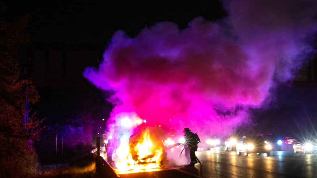 Car on fire night accident on the highway road with police.