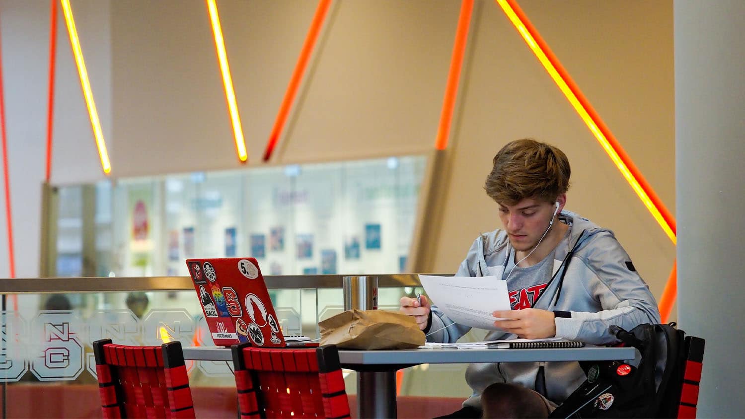 A student reads from a sheet of paper while seated at a table