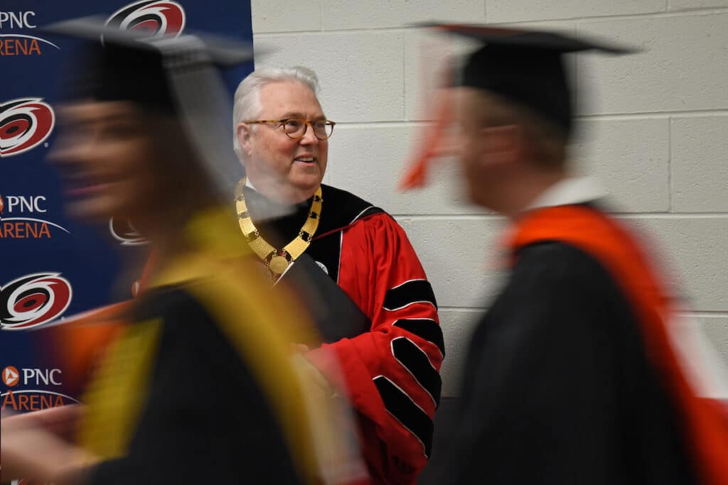 Chancellor Randy Woodson congratulates graduate students as they walk into PNC Arena for commencement.