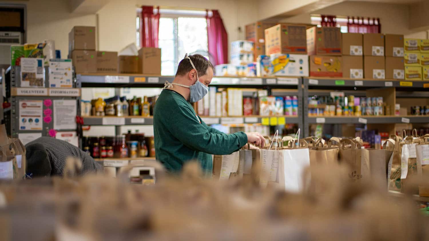 man sorts through bags in a charity food pantry