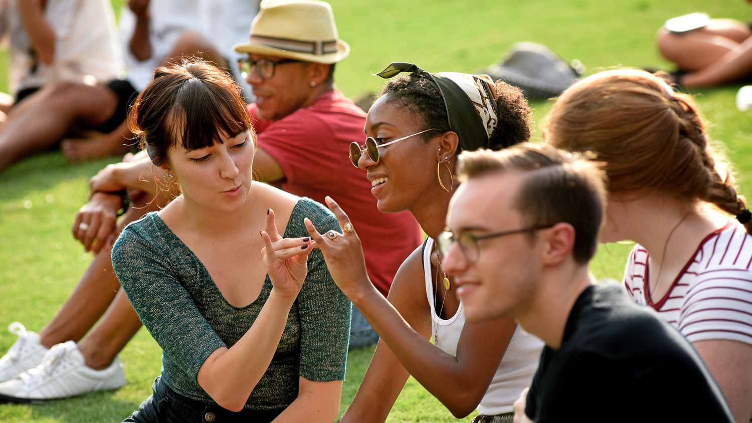 Students practice making wuf hands while attending the WKNC Concert on the Lawn during Wolfpack Welcome Week.