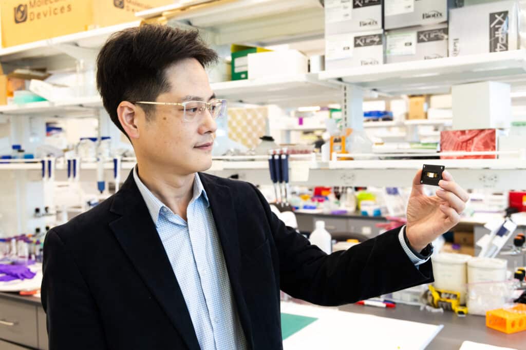 Wearing a black jacket and glasses, Qingshan Wei leads N.C. PSI project called WolfSens. Inside one of the labs in the Plant Sciences building, he holds up a small sensor.