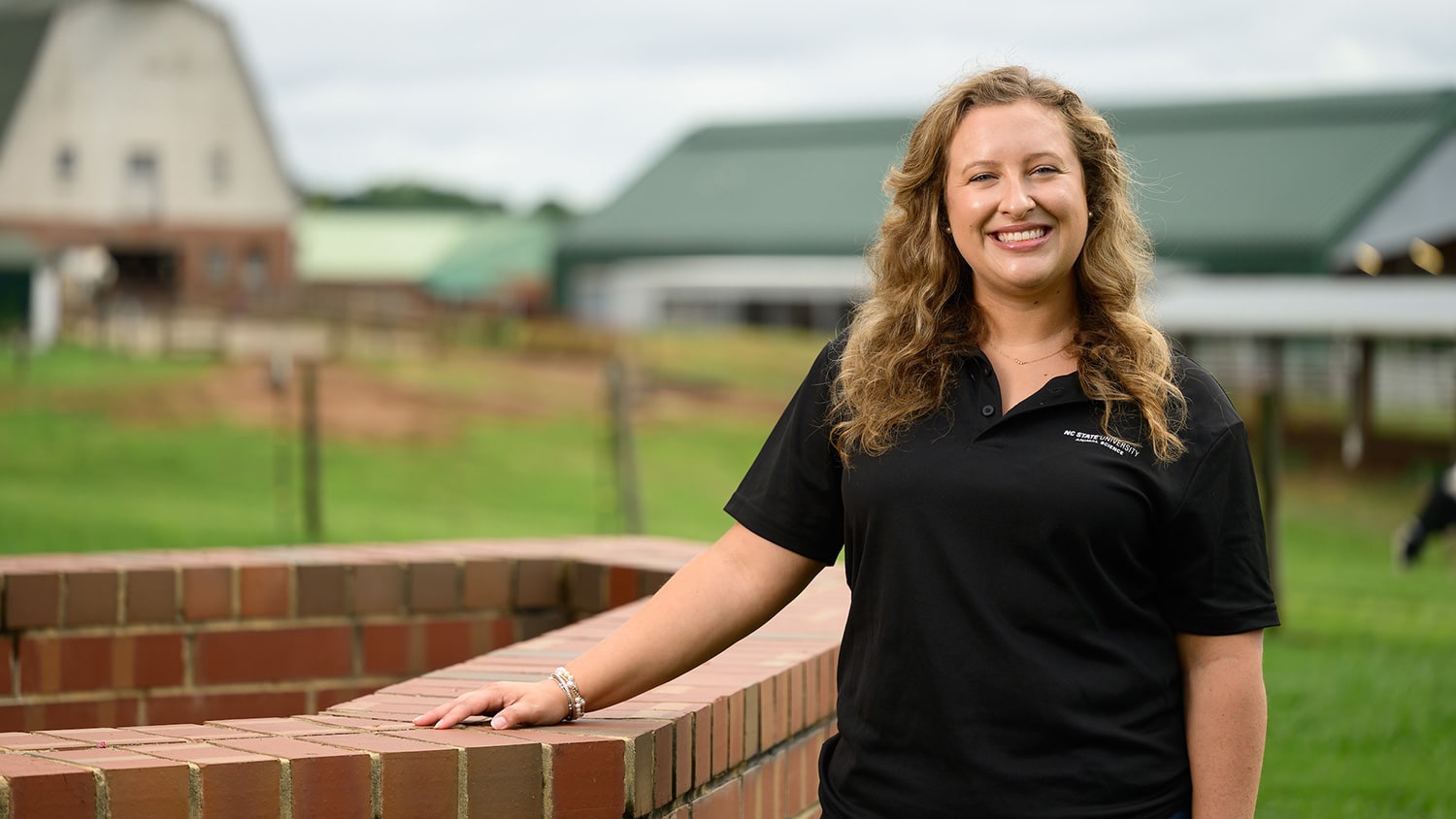 A portrait of Lindsey Britton taken outside in front of a barn.