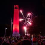 A shot of the Belltower, lighted red, with red fireworks exploding in the darkened sky to the Belltower's right.