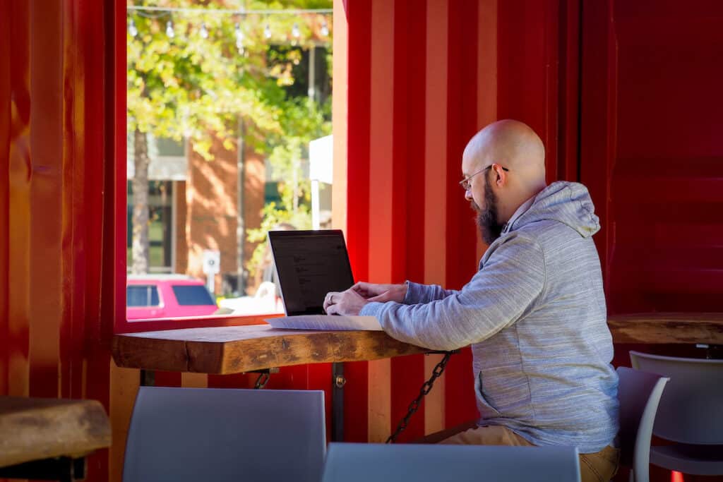 A student works on a laptop inside one of the repurposed storage containers at The Corner